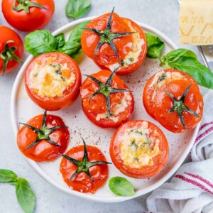 top view baked tomatoes stuffed with cheese on a white plate