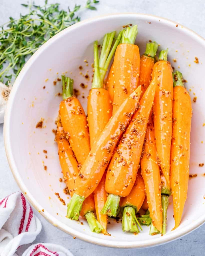 Coating whole carrots in a honey mustard sauce.