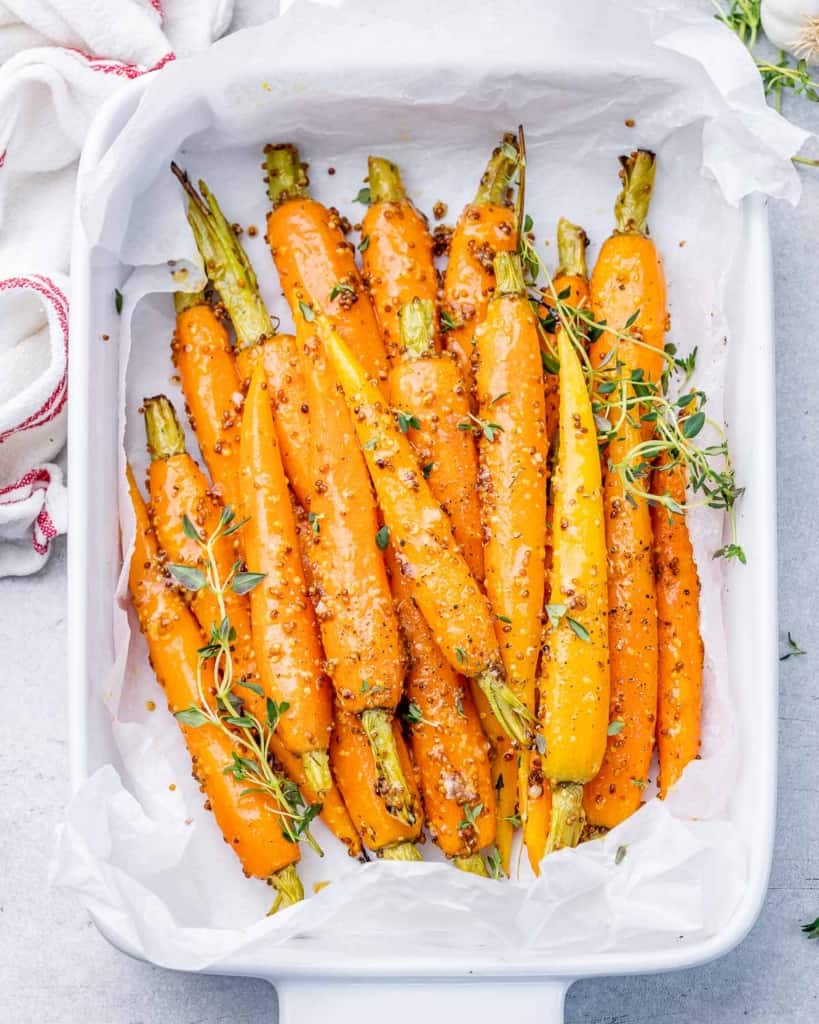 Top view of roasted carrots in a honey mustard sauce in a white dish.