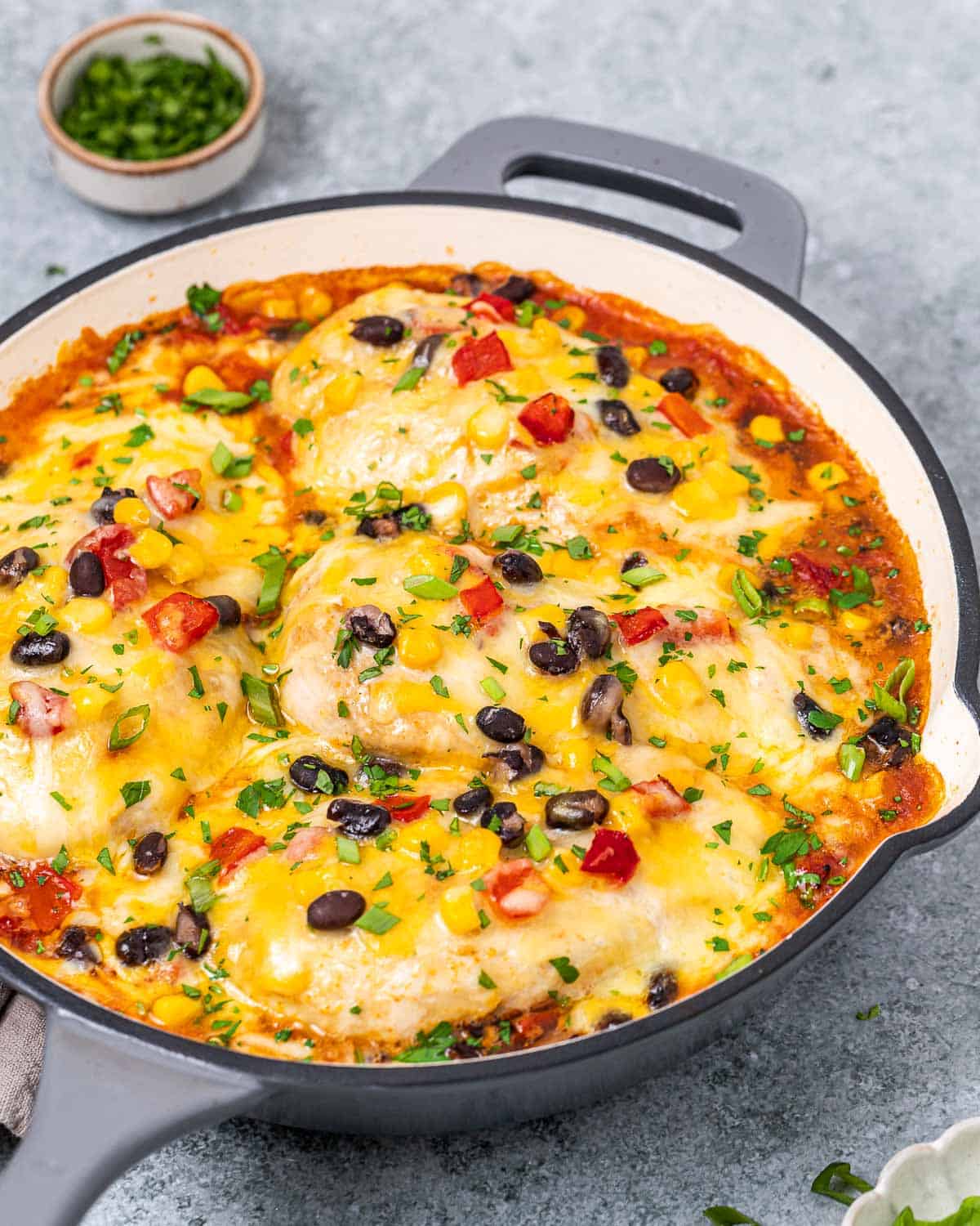 Round skillet filled with baked Santa Fe chicken breasts in a cheesy, colorful vegetable mixture.