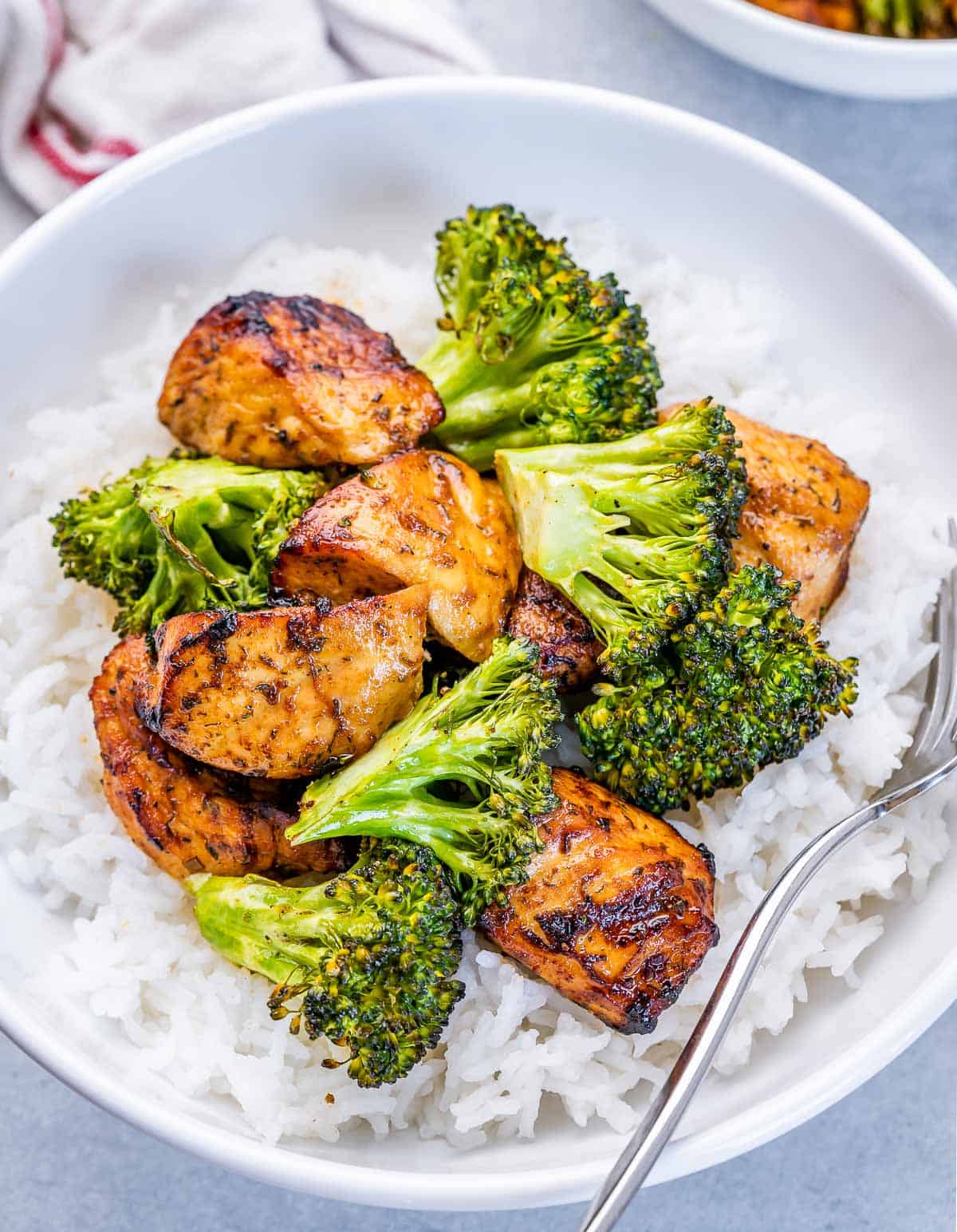 Air fryer chicken and broccoli served over white rice in a white bowl.