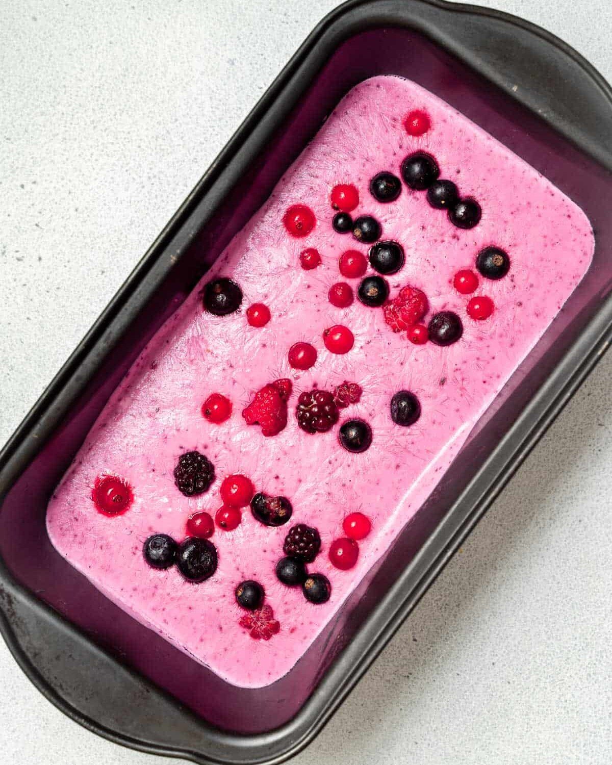 Cottage cheese ice cream in a loaf pan topped with berries.