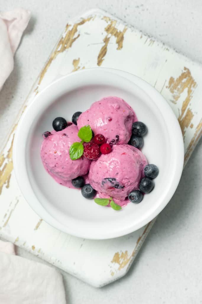 top view cottage cheese berries icecream in a bowl. it has a bright pink look with fresh berries on top