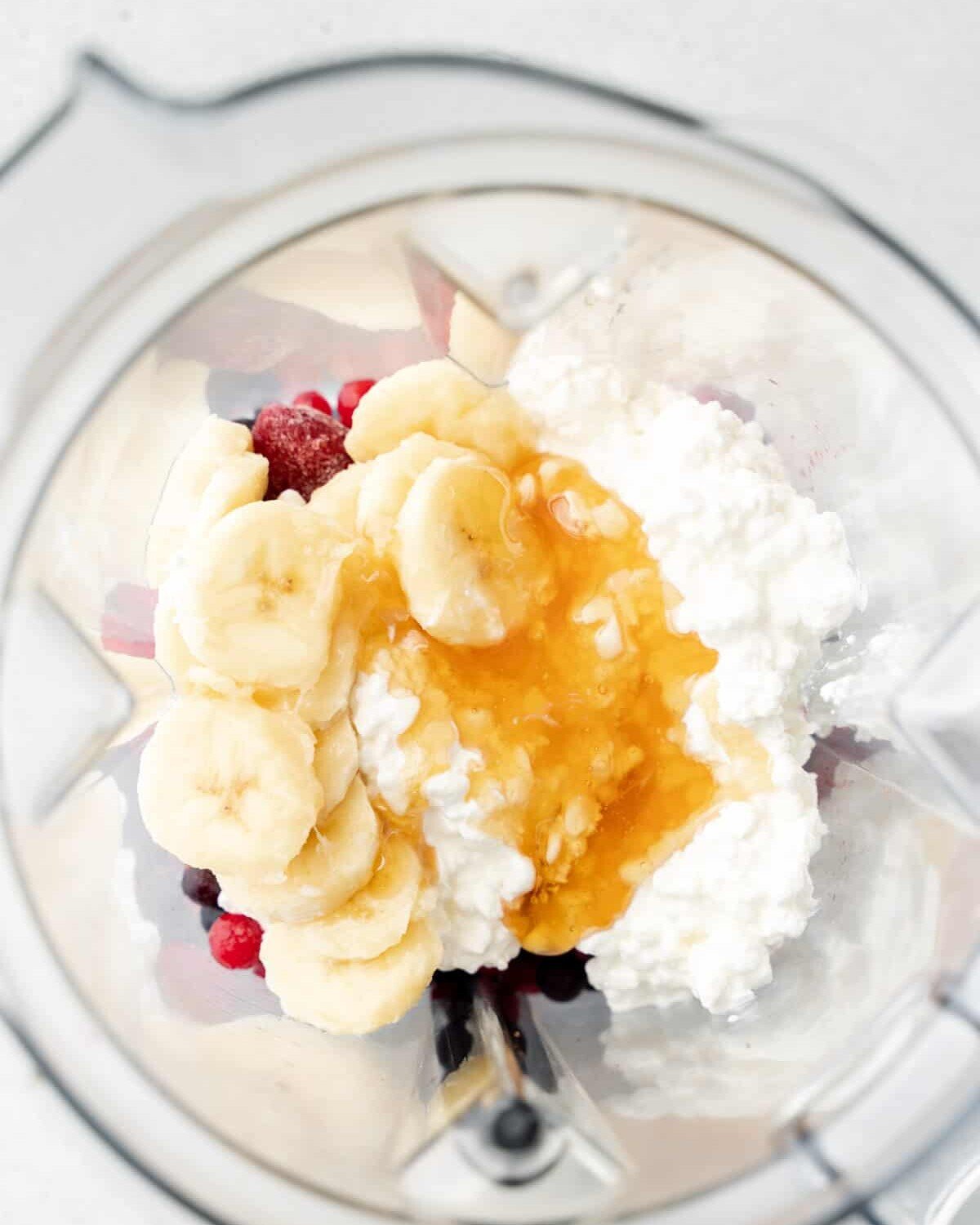 Frozen berries, cottage cheese, honey, and banana slices in a blender.