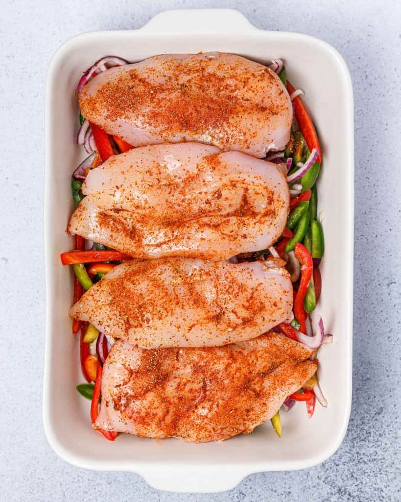 seasonings over chicken breast with shredded bell peppers