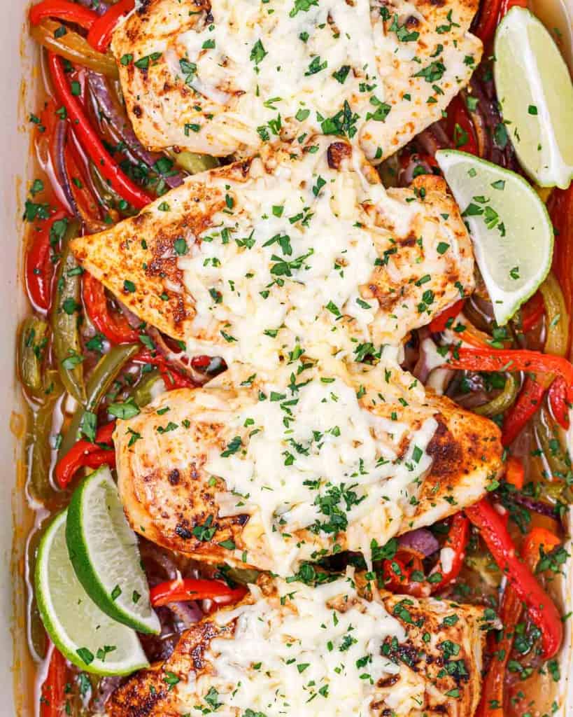 top view baked chicken breast over a bed of peppers in a white dish