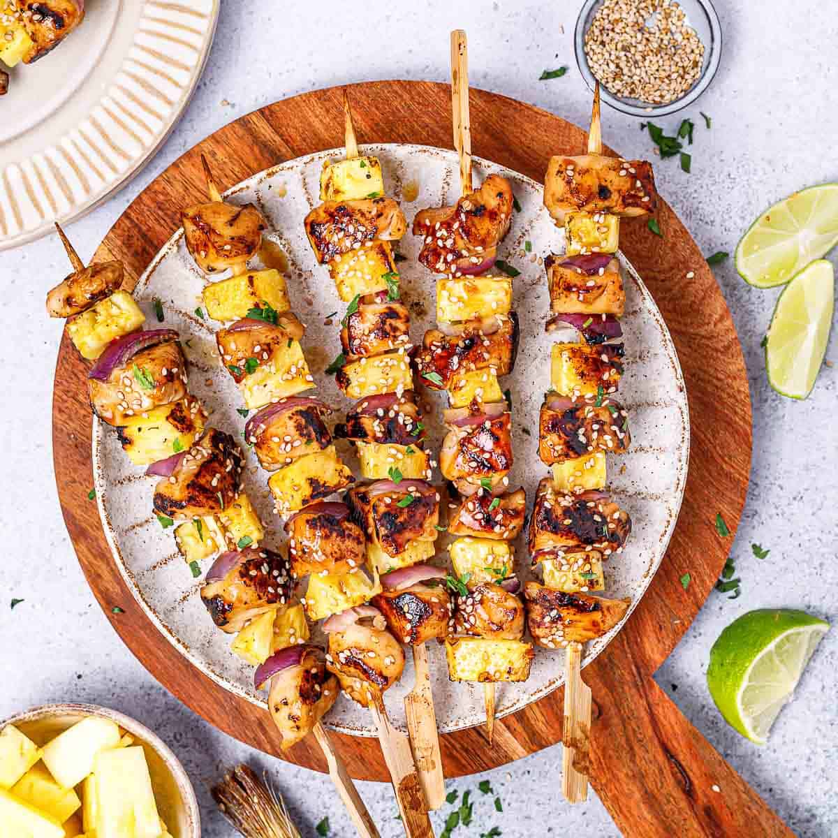 top view of 5 grilled chicken skewers on a white round plate