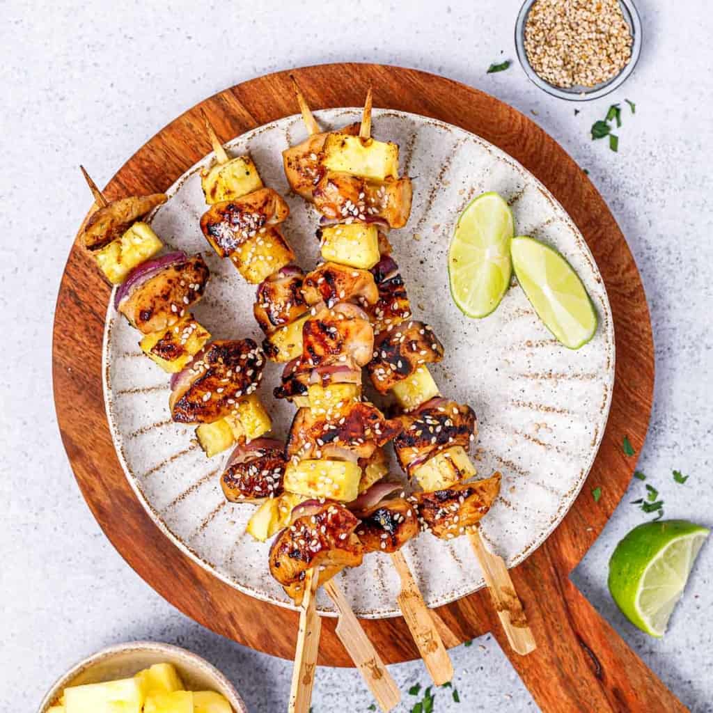 image of 4 chicken skewers on a round plate with lime wedged on the side
