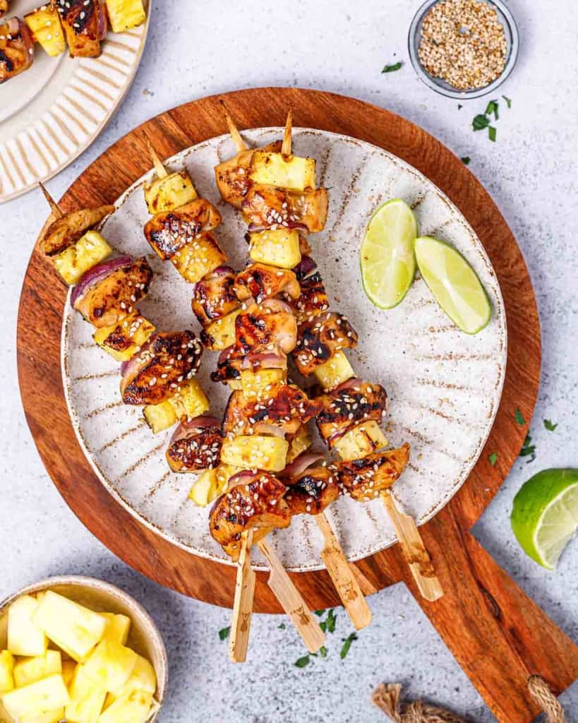 Grilled teriyaki chicken skewers made with pineapple and red onion on a plate.