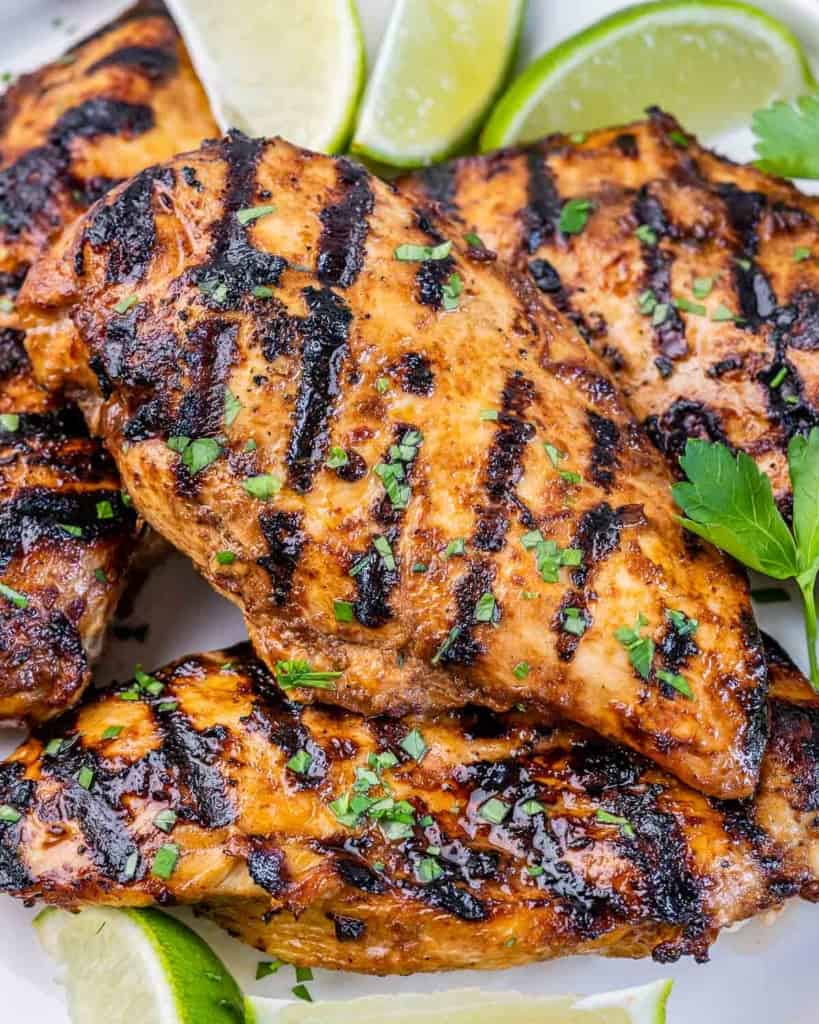 Honey chipotle grilled chicken served with lime wedges on a white platter.