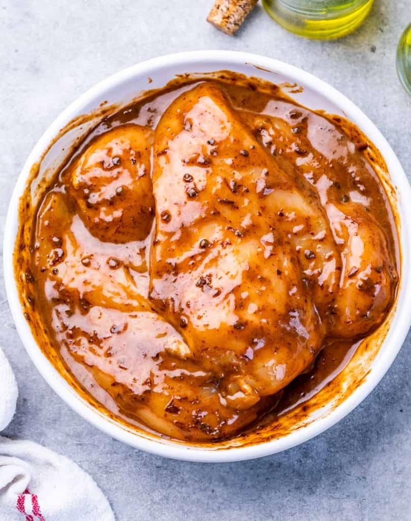 Marinating chicken breasts in a white bowl.