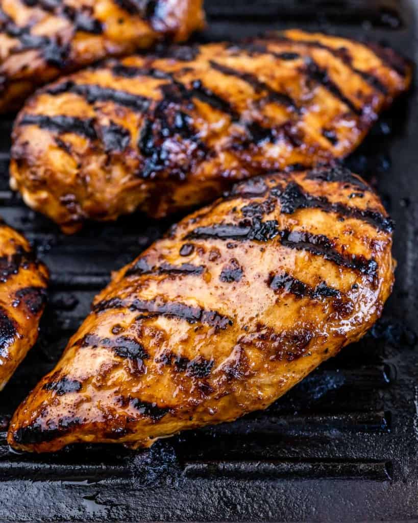 Chicken breasts grilling with grill marks.