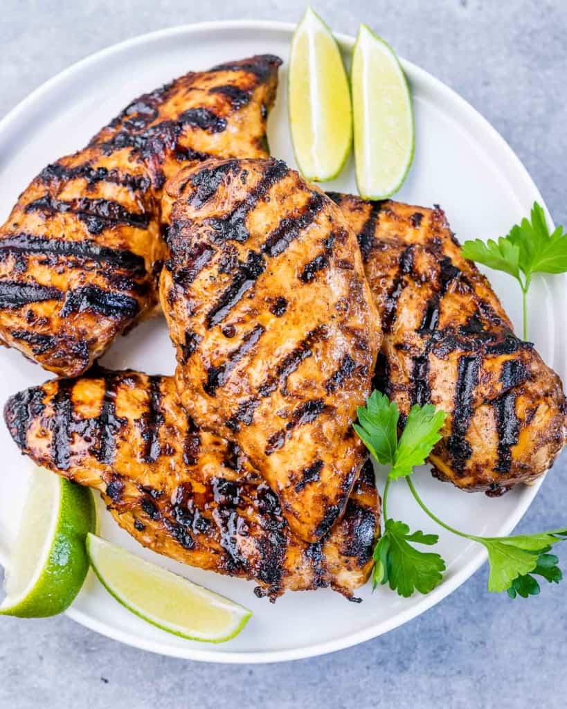 top view of grilled chicken on a plate with lime slices