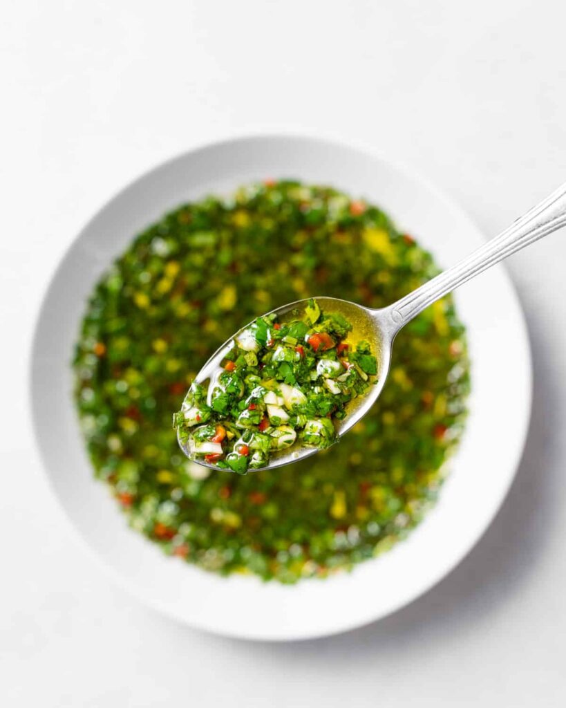 top view of a bowl with chimichurri with spoonful of sauce