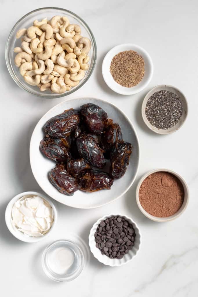 Dates, nuts, cocoa powder and flax divided into small bowls.