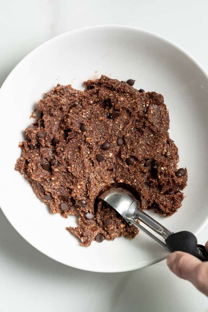 Scooping up energy ball mixture with a cookie scoop.