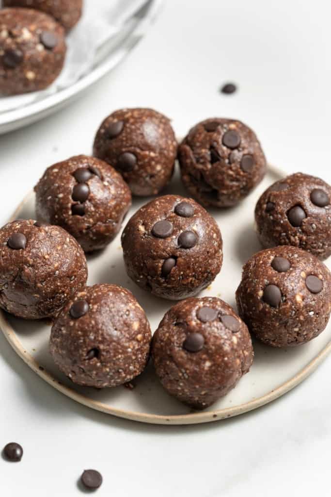 Energy balls made with cocoa powder and chocolate chips on a plate.