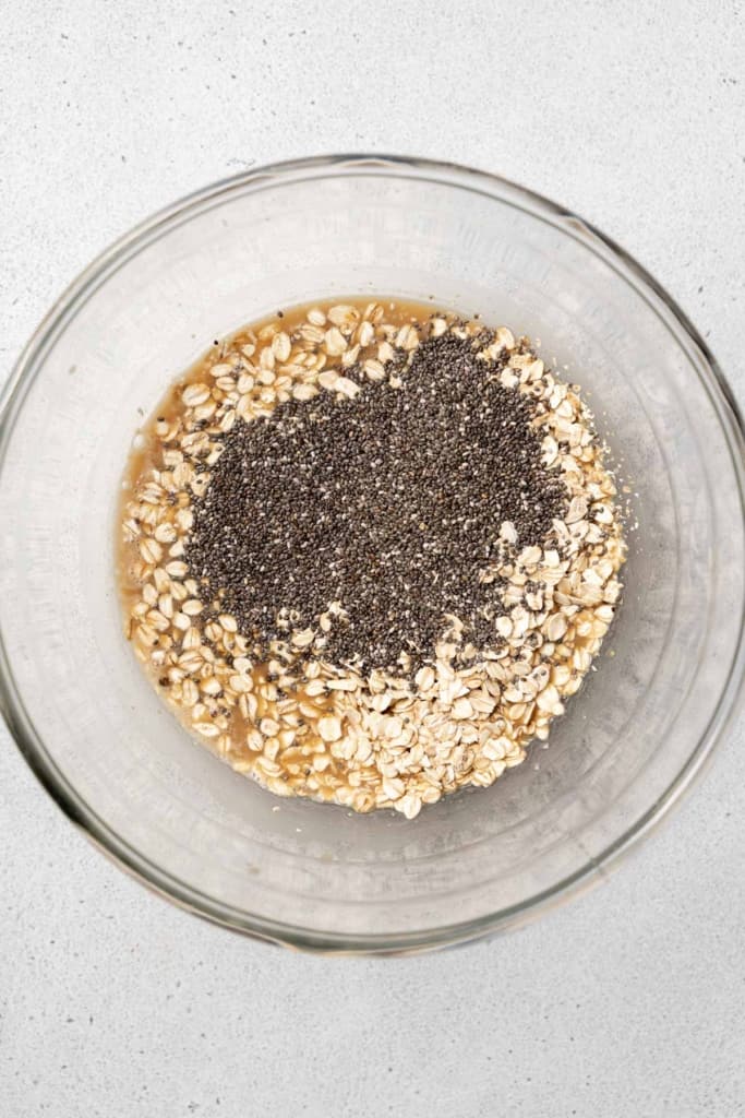 Adding chia seeds to oats in a bowl.