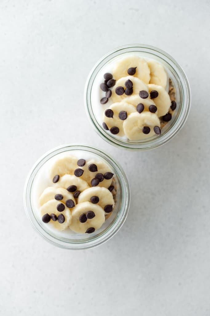 Topping overnight oats with bananas and chocolate chips.