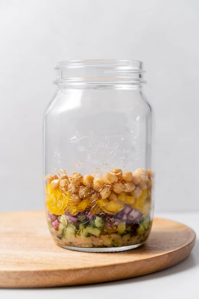 Chopped peppers and chickpeas added to the jar