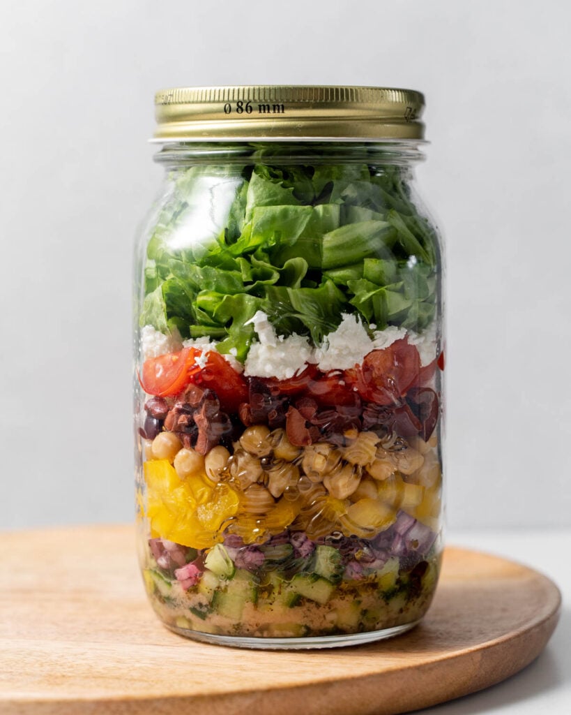 lid added over a jar filled with salad ingredients neal prepped to make Greek salad