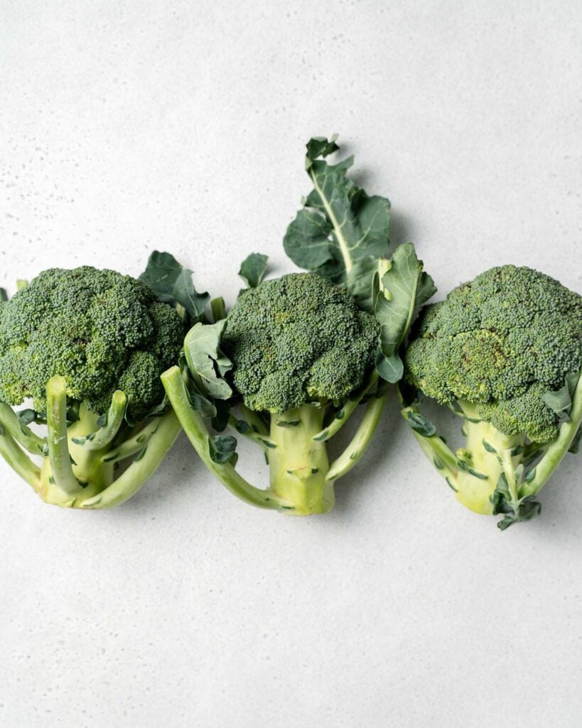 3 heads of broccoli next to each other on a flat surface