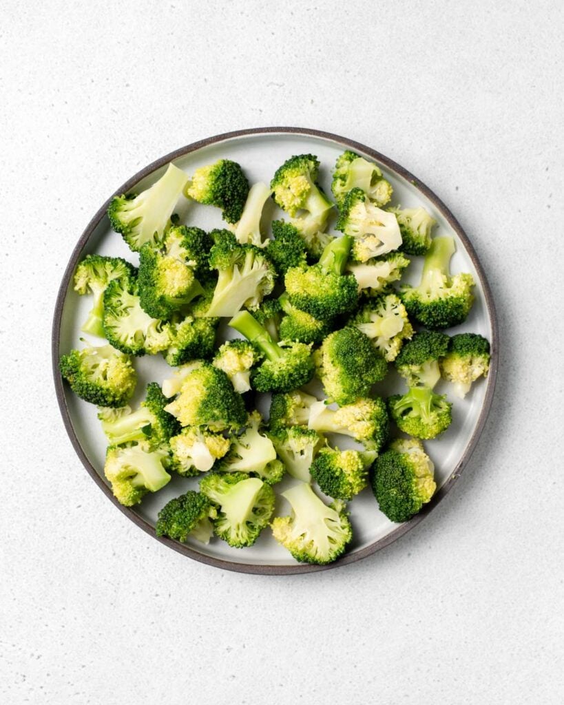 top view of cooked steamed broccoli florets on a round plate