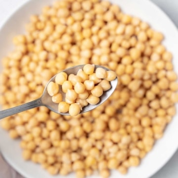 spoonful of cooked chickpeas over a plate full of chickpeas