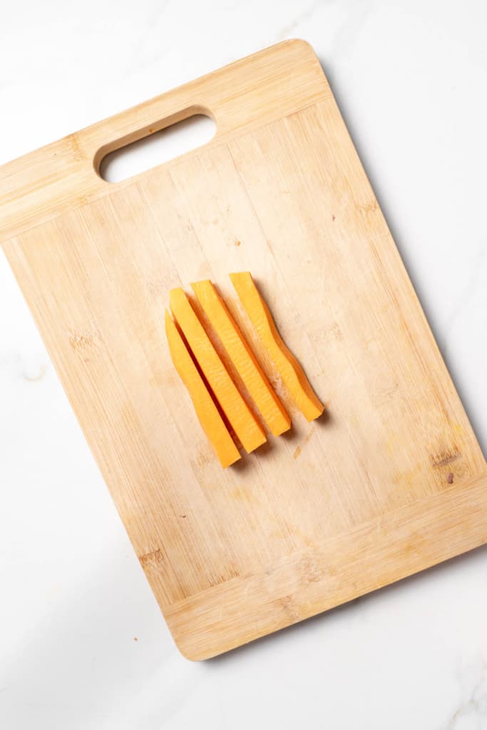 Long sticks of a sweet potato on a cutting board.