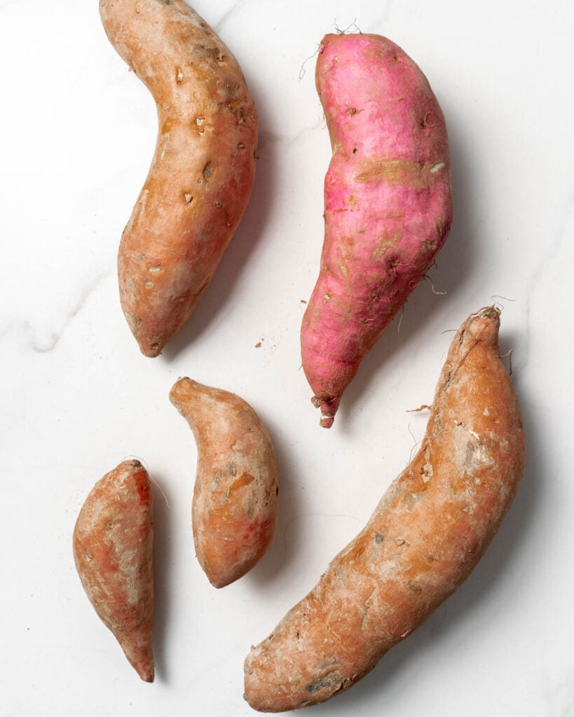 5 different size and color sweet potatoes on a flat surface