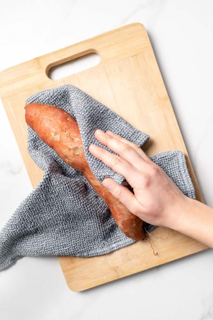Using a kitchen towel to dry off a sweet potato.