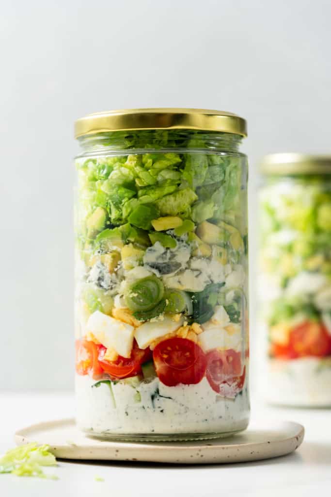 Vegetarian Cobb salad stored in a glass jar with a gold lid.