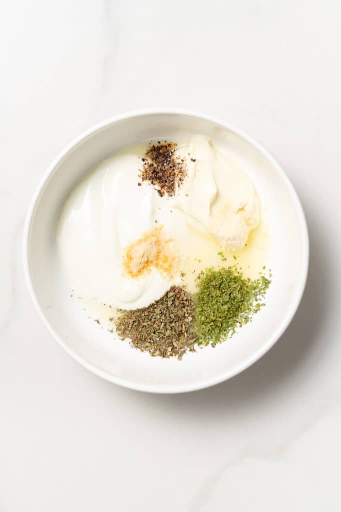 Mayo, Greek yogurt and seasonings added to a white bowl.