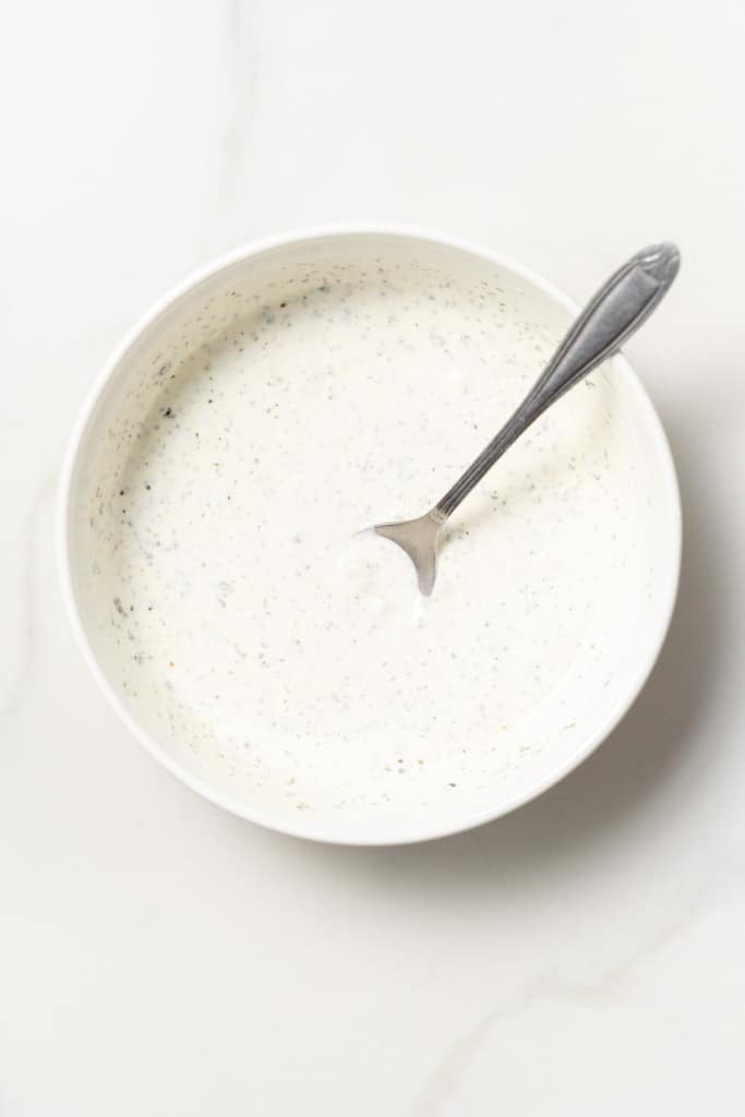 Whisking homemade ranch dressing in a bowl.