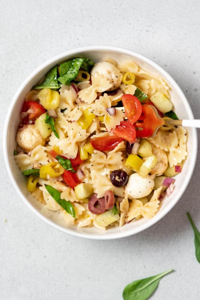 Italian pasta salad in a white bowl with a fork.