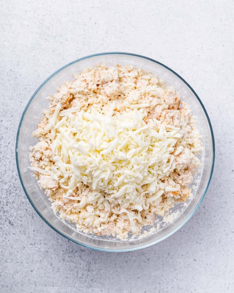Adding shredded cheese to chicken and rice mixture.
