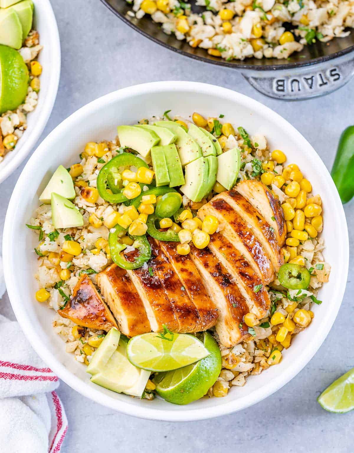 Chipotle chicken rice bowl served with sliced avocado and lime wedges.