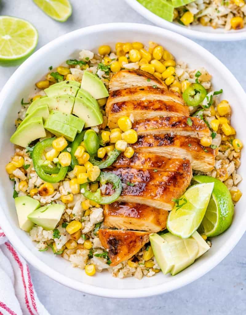 top view of a white bowl with cauliflower rice, corn, and sliced cooked chicken breast