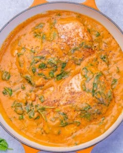 Overhead shot of salmon cooking in a thick spinach and roasted red pepper sauce.