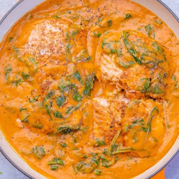 Salmon filets covered in creamy spinach sauce, filling the skillet from edge to edge.