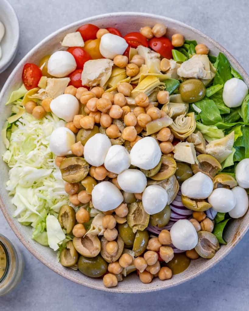 mozzarella balls, chickpeas, and other veggies added over a salad bowl