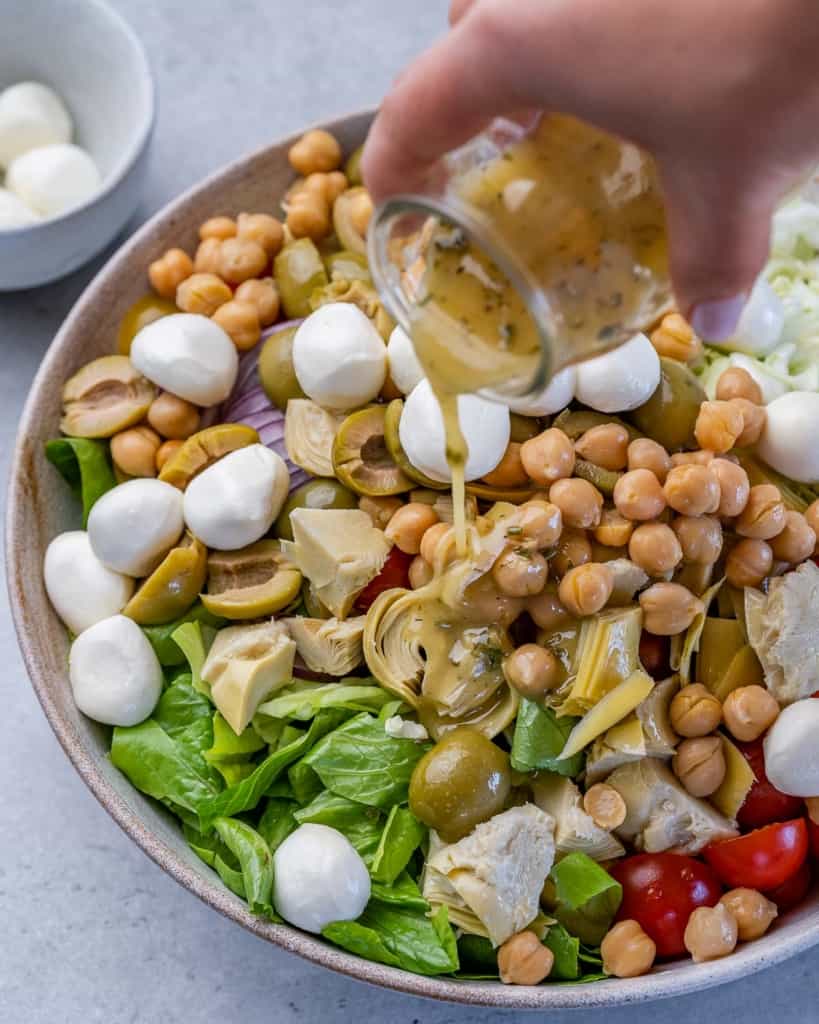 dressing being added over chopped salad 