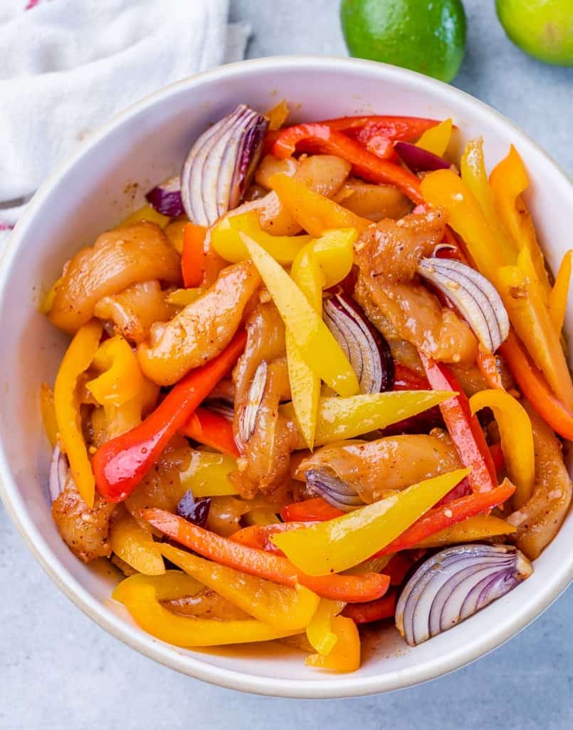 Marinating chicken and veggies in a white bowl.