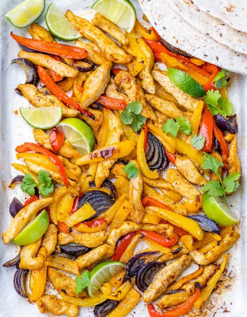 Chicken fajitas cooked on a parchment-lined sheet pan.