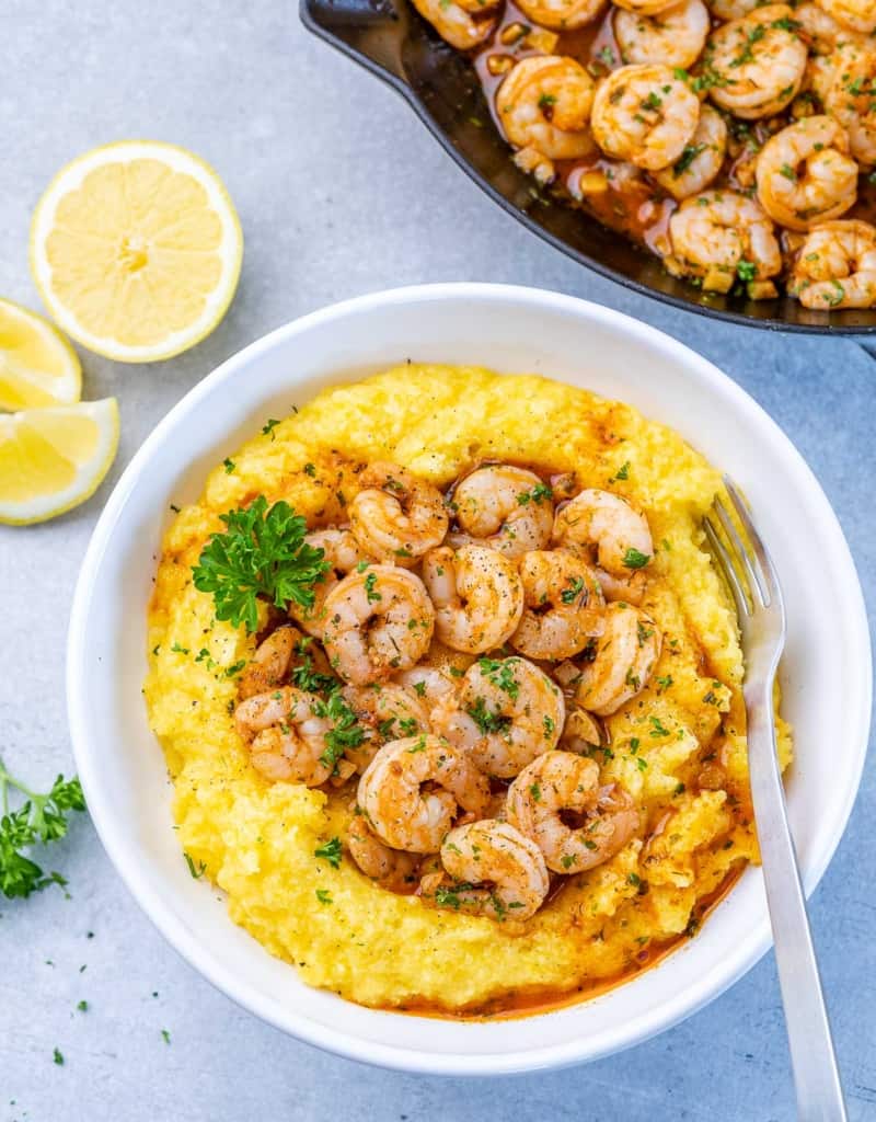 top view of a white bowl with yellow looking grits topped with shrimp