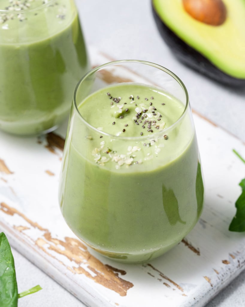 Side shot of a glass with a green avocado smoothie.