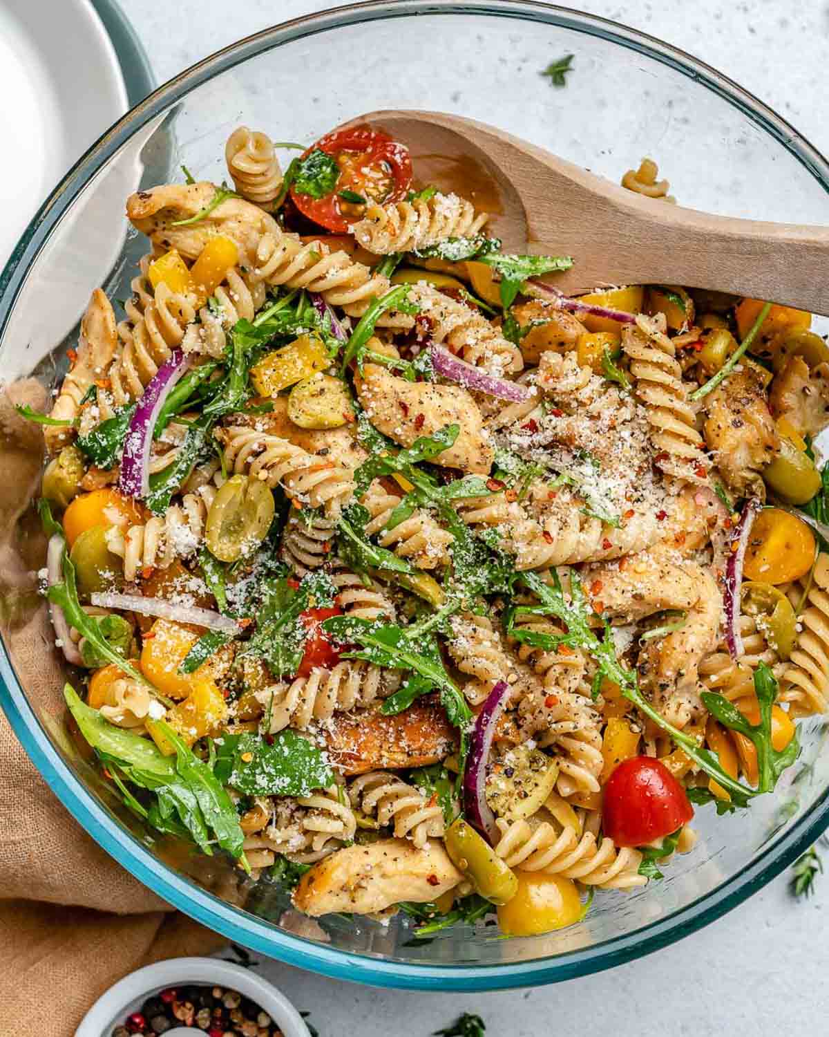 a clear bowl with pasta salad made with chicken and veggies.
