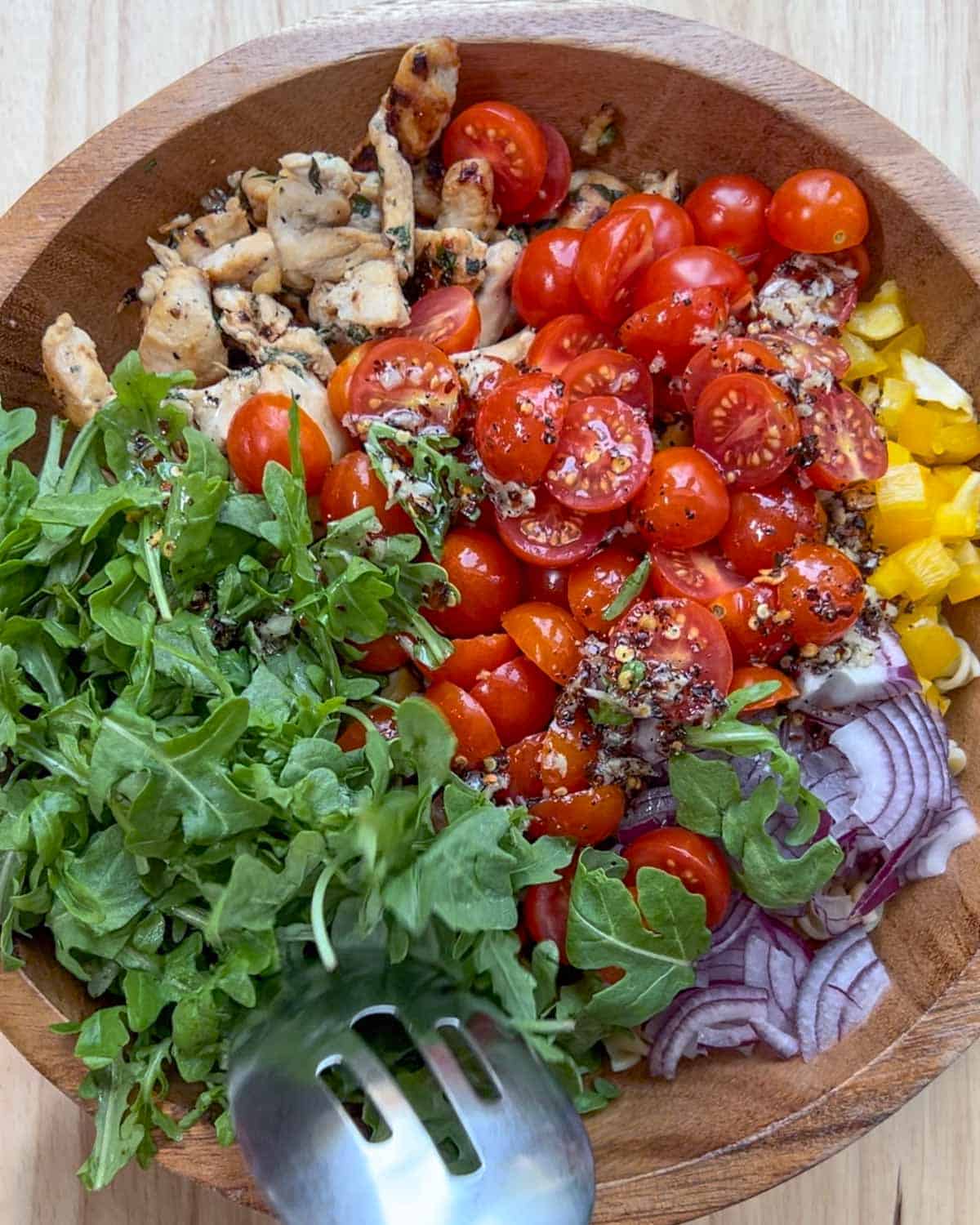 chicken pasta salad ingredients are added to a bowl before mixing.