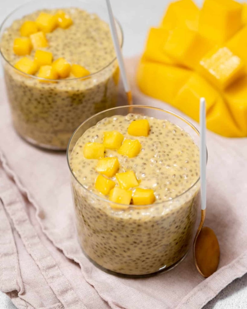 side and top shot of two cups of mango chia pudding in a cup topped with fresh chopped mango
