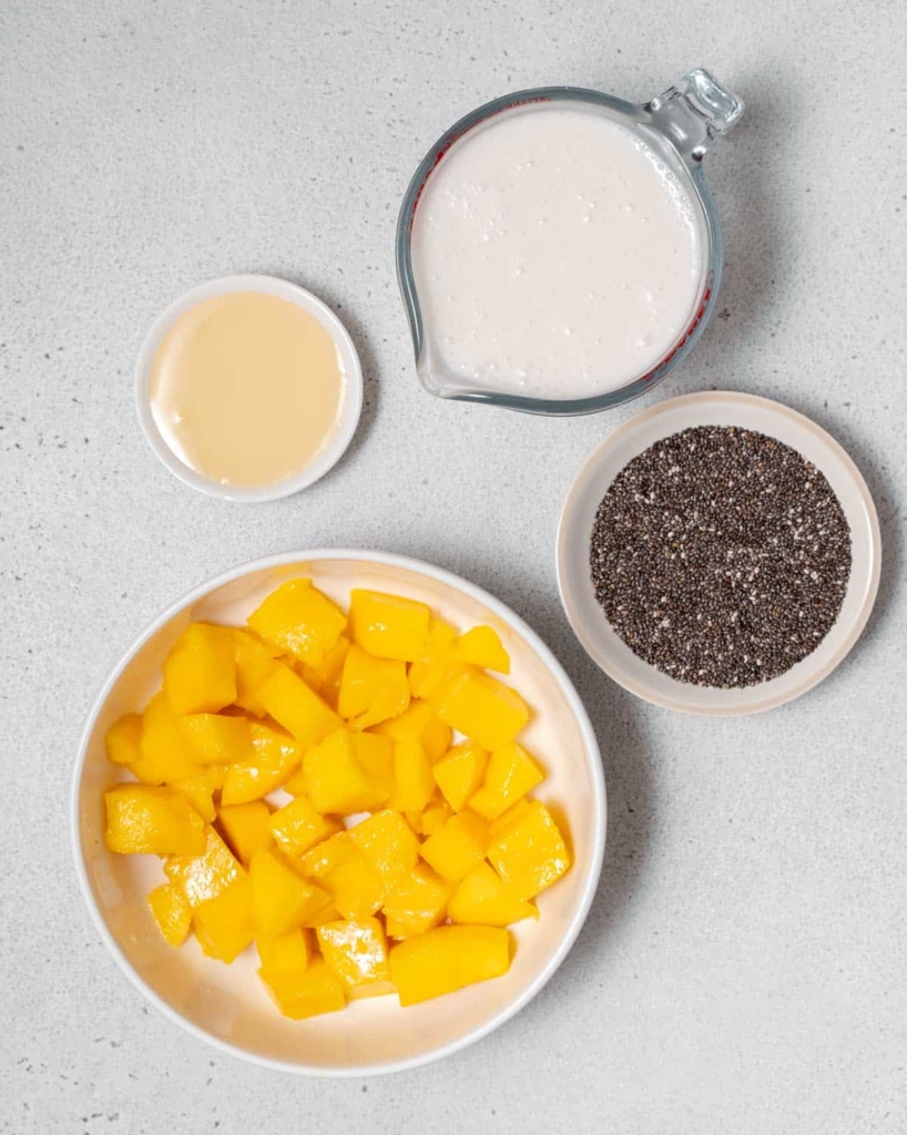 4 ingredients laid out to make mango chia pudding. fresh mangos, chia seeds, agave, and coconut milk